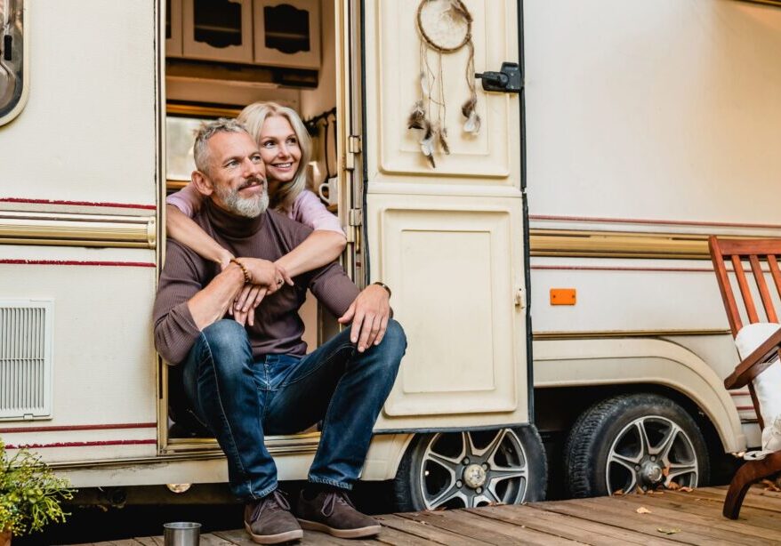 A man and woman sitting on the steps of an rv.